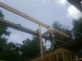 Carpenter setting a ridge beam over a new addition frame — Ice Dam Removal by Roofing Brothers in Coopersville