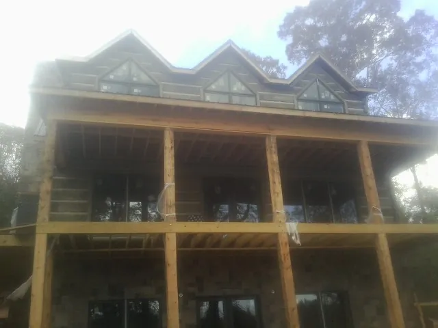 Dormers and porch framing on a large log home under construction — Roof Coating work by our crew in Coopersville