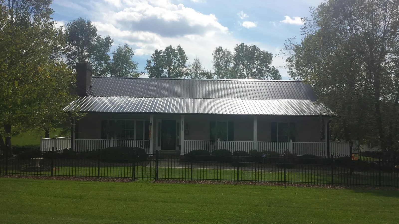 Gray metal roof on a brick ranch with a full width front porch — Gutter Guard Installation work by our crew in Coopersville