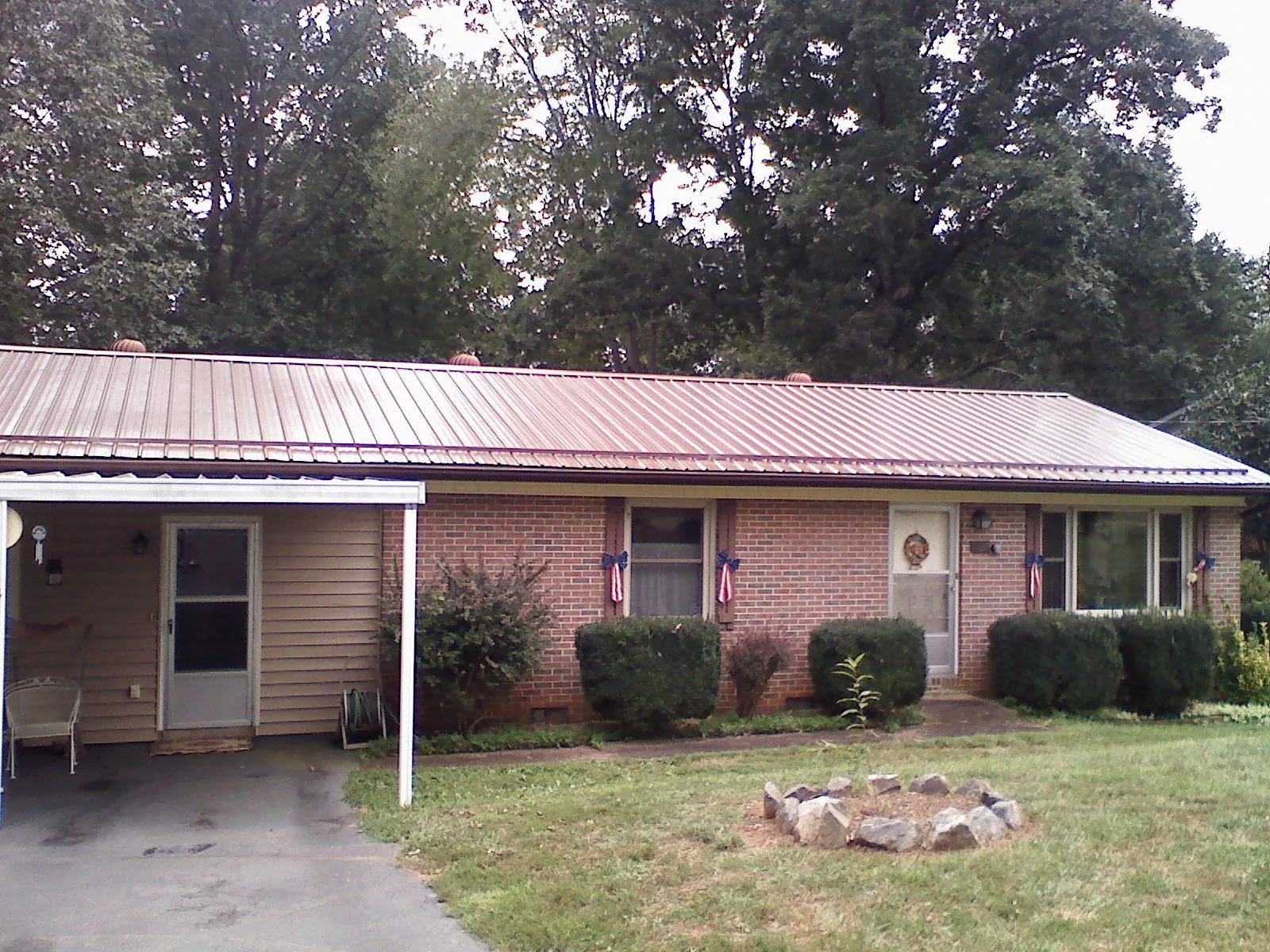 Bronze metal roof and carport on a brick ranch home — Roof Repair work by our crew in Coopersville